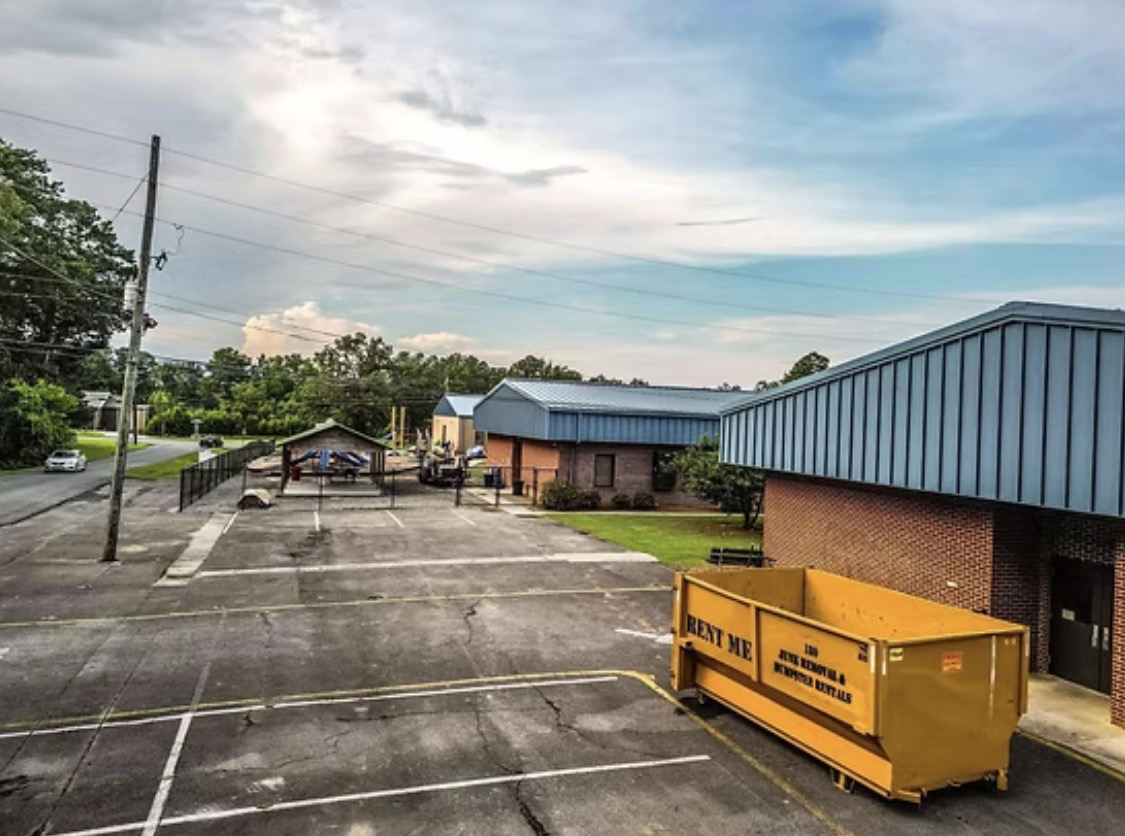 Yellow 180 roll-off dumpster placed outside a commercial building
