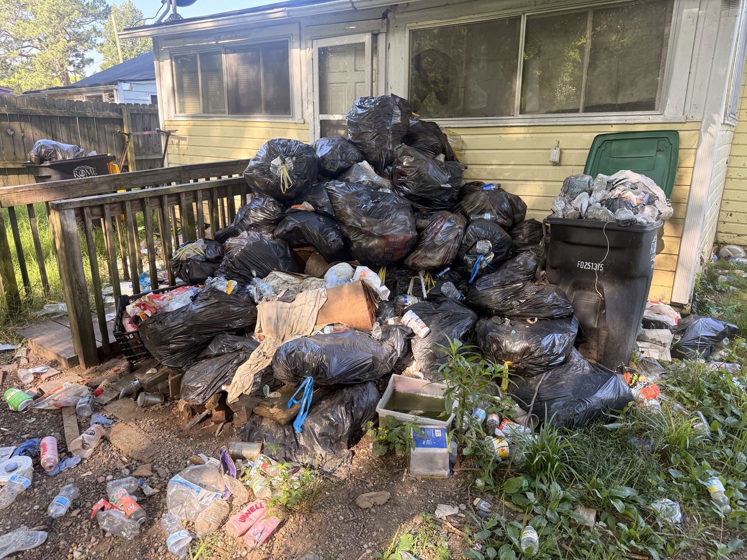 Bagged trash and loose debris gathered outside a home for removal